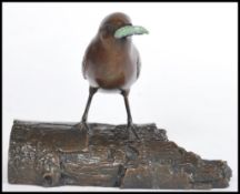 A cold cast bronze figurine of a wren perched on a log with a green grub in its beak by Eddie