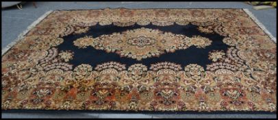 An early 20th Century very large woven woollen floor rug on dark ground, traditional style