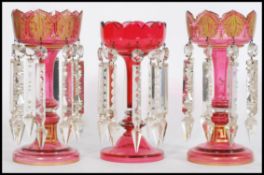 A 19th century Victorian garniture of cranberry glass lustres, to include two matching with with