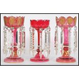 A 19th century Victorian garniture of cranberry glass lustres, to include two matching with with