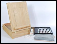 A 20th Century metamorphic artist box easel containing various paints and pastels, carrying handle