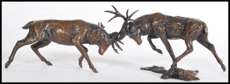 A bronze figuring of two rutting stags on an incorporated base by Michael Simpson, baring the