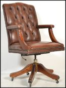An antique style tan brown leather and mahogany office swivel esk chair raised on a splayed mahogany