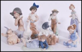 A collection of nine porcelain ceramic groups by Nao and Lladro to include dogs, boys, girls,