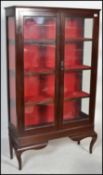 An Edwardian mahogany display cabinet on stand. Raised on shaped legs with a tall twin door