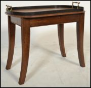 An early 20th century Edwardian mahogany tray on stand raised n splayed legs with shaped brass