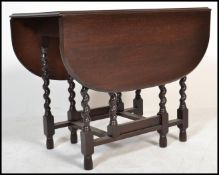 A 1930's solid oak barley twist drop leaf extending pad foot dining table with gate leg action