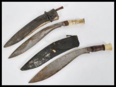 A pair of 20th century Kukuri knives with curved blades in wooden and leather sheaths having bone