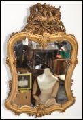 A 20th century Regency revival French wooden framed carved gilt wall mirror having a shaped frame