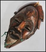 A 20th carved African Tribal hardwood mask of unusual form applied with twist metal wirework