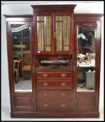 A Victorian mahogany Art Nouveau triple compactum breakfront wardrobe armoire being raised on a