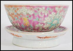 A 19th century famille rose canton enamel bowl and stand having floral scrollwork and painted