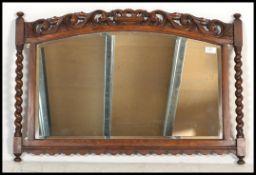An early 20th Century Edwardian oak framed bevel edged wall mirror of architectural form with barley