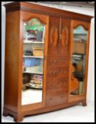 An Edwardian mahogany triple wardrobe compactum armoire. Raised on a plinth base with central