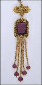 A vintage signed gold-tone drop necklace with large faceted purple glass stone with purple finial