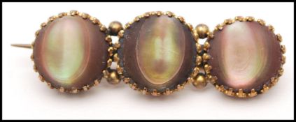 A Victorian yellow metal bar brooch pin set with three abalone / mother of pearl cabochons having