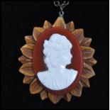 An Art Deco carved wood and bakelite cameo pendant necklace being strung on a decorative black metal