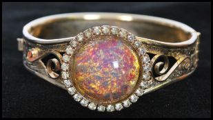 A 1980s gold-tone bracelet bangle set with large faux opal cabochon surrounded with a halo of