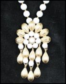 A vintage signed Trifari gold tone and white glass bead flower pendant necklace. Chain measures 18