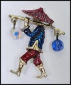 A signed Corocraft Chinese water carrier brooch decorated with enamel having AB glass bead