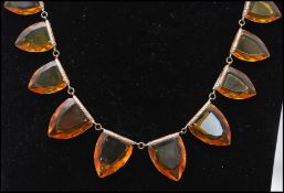 A 1920s Czech signed amber glass riviere necklace with stylized faceted amber glass stones with
