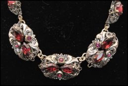 A 1920s Czech parure, set with amethyst glass and rhinestones set in 3d filigree work, to include