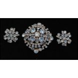 A 1950s silver tone oversized rhinestone brooch and earring set being set with pale blue