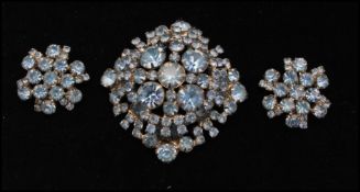 A 1950s silver tone oversized rhinestone brooch and earring set being set with pale blue
