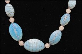 A 1930s Czech moulded uranium glass bead necklace being strung with baby blue and opaline beads with