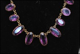 A 1920s Czech gold-tone amethyst glass riviere necklace having rhinestone embellished clip clasp.