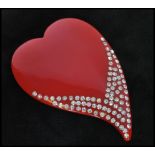 An early 20th century oversized red lucite brooch in the form of a heart with paste embellishment.