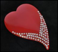 An early 20th century oversized red lucite brooch in the form of a heart with paste embellishment.