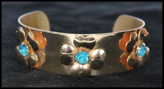 A 1960s rhinestone set gold tone cuff bangle having blue rhinestones in flower settings.