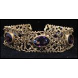 A 1920s gold-tone filigree work 5 link panel bracelet set with faceted amethyst glass. Measures