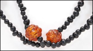 A 1930s vintage French jet black glass necklace strung with amber art glass beads together with a