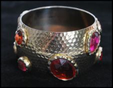 A 1960's gold tone oversized bangle set with large faceted pink and orange stones with planished