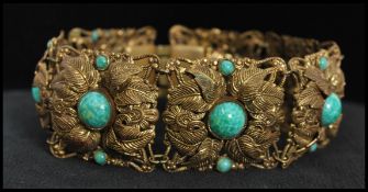 A 1920's Czech gold tone bracelet set with peking glass cabochons with filigree and foliate work