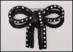 A large 1930s extruded bakelite brooch in the form of a bow set with paste stones. Measures 3
