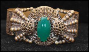 A 1930s gold-tone Etruscan revival bracelet bangle set with a green cabochon. Measures 2 1/2