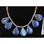 A collection of 3 white metal ethnic necklaces one set with lapis lazuli tear drops, one having a