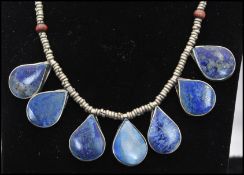 A collection of 3 white metal ethnic necklaces one set with lapis lazuli tear drops, one having a