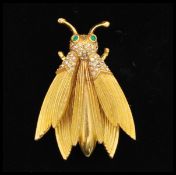 a 1950s large gold-tone trembler bug brooch with green rhinestone set eyes. Measures 2 inches.