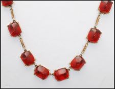 A 1920s German gold-tone red scarab glass cabochon riviere necklace having stylised cabochons.