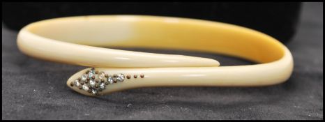 A Victorian carved ox bone snake bangle with paste set head. Diameter approx 3 1/4 inches.