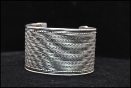 A vintage white metal cuff bangle having filigree decoration. Width approx 4cm. Weight 43.g