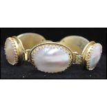 A signed vintage Whiting and Davis tooled gold tone mother of pearl bracelet being set with five