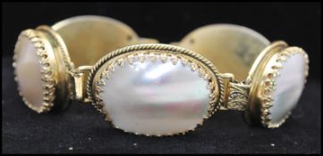 A signed vintage Whiting and Davis tooled gold tone mother of pearl bracelet being set with five