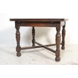 A 1930's oak draw leaf refectory dining table being raised on turned legs united by stretcher having