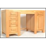 A contemporary solid oak twin pedestal desk, having an arrangement of nine drawers fitted with