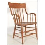 A 20th century American Windsor style country oak armchair raised on turned legs united by stretcher